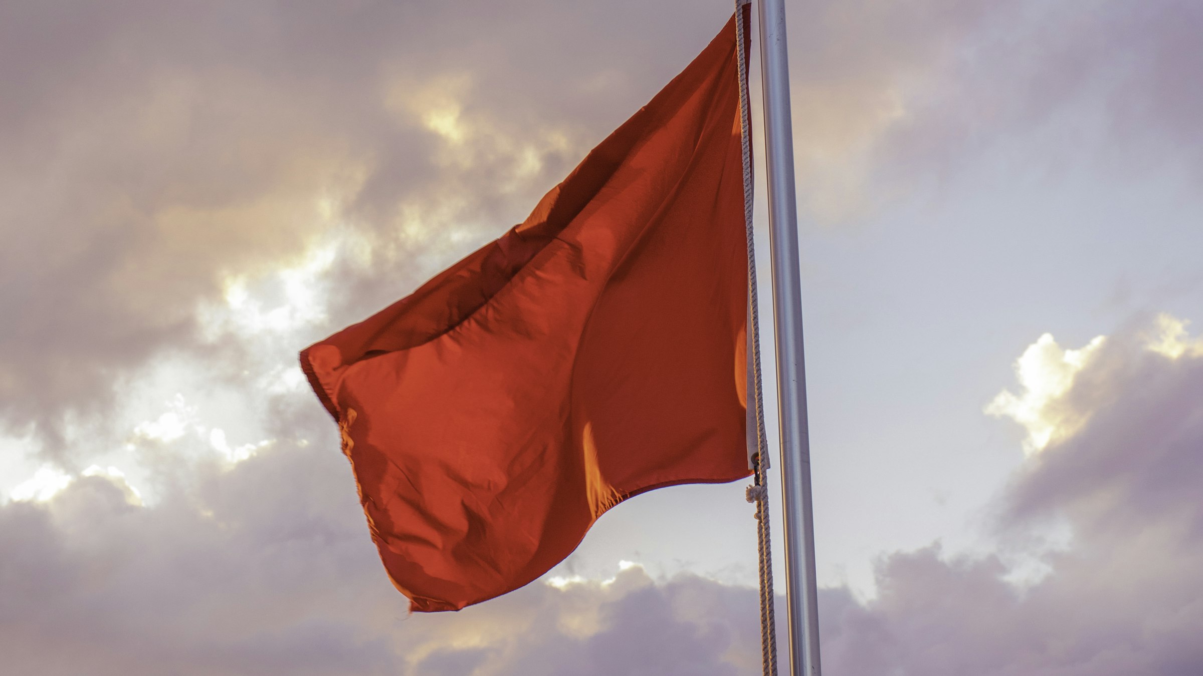 A red flag waving against a dramatic sky