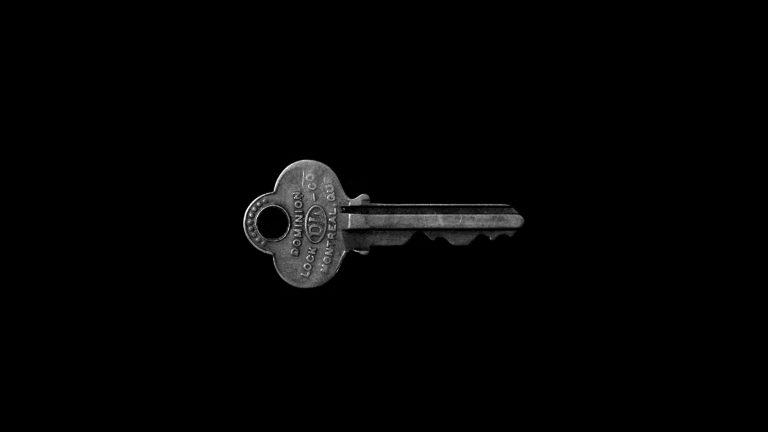 A single metal key lit against a black background